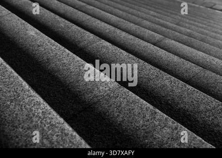 A black and white photo of a staircase. The stairs are made of stone and are very long Stock Photo