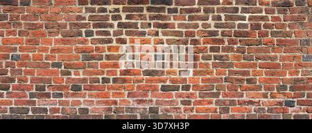 Old brick wall made of red and dark bricks with bright joints Stock Photo