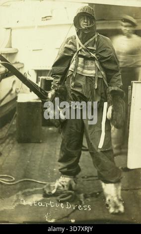 Postcard showing a crew member in "Antartic (sic) Dress" demonstrating the full outfit used on the expedition.  Although nearly thirty years old at the time of Captain Scott's expedition, Terra Nova was chosen for it because of her suitability for work in the Antarctic ice. Her beams were fourteen ins thick, her bows were nine feet of solid wood, and her stem was sheathed with iron plating. Stock Photo