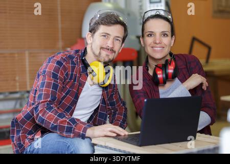 young couple with laptop in the carpenter workroom Stock Photo