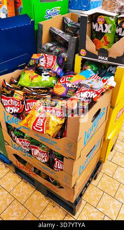 ISERLOHN, GERMANY — NOVEMBER 27 2025: stacked cardboard boxes filled with assorted chips displayed inside Lidl store today Stock Photo