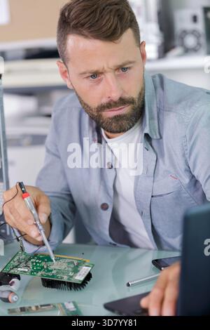 man is repairing broken pc with a screw driver Stock Photo