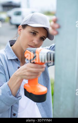 young female builder drilling a hole in the wall Stock Photo
