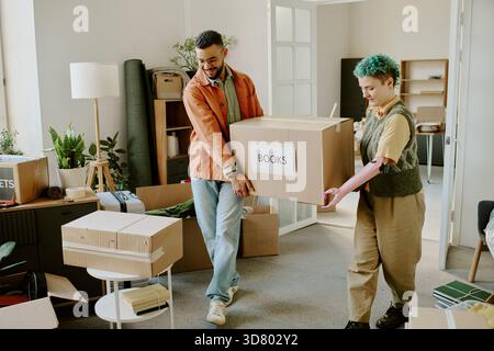 Young Multiethnic Couple Carrying Boxes While Moving and Renovating Apartment Stock Photo