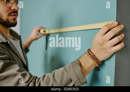 Young Adult Man Measuring Wall While Doing Home Renovations Stock Photo