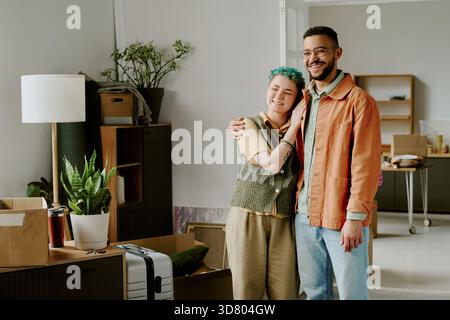 Young Multiethnic Couple Smiling and Embracing While Settling into New Apartment Stock Photo