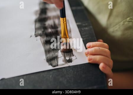 focused art student skillfully crafting monochrome brushwork in peaceful studio environment Stock Photo
