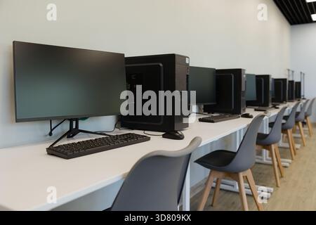 In a contemporary setting, multiple computers sit ready for use, providing an ideal space for focused work and collaboration. Stock Photo