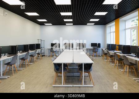 Bright and airy workspace featuring multiple computer stations, stylish furniture, and ample natural light flowing in. Stock Photo