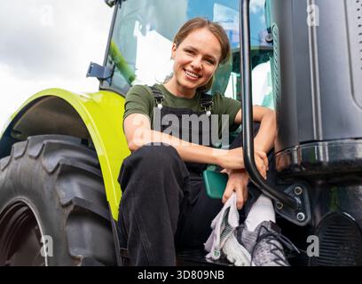 Rural lifestyle woman on tractor in farmland Stock Photo