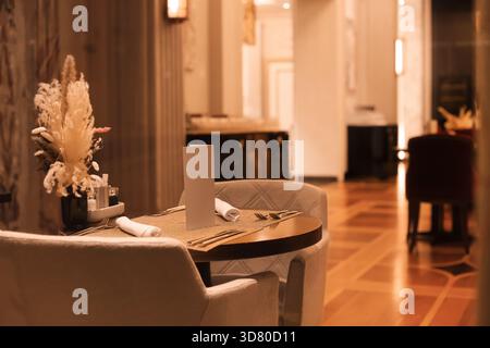 Set table with elegant chairs, blank menu, and dried flower centerpiece in a dimly lit, luxurious restaurant interior. High quality photo Stock Photo