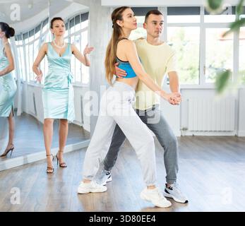 Couple practicing passionate tango guided by female dance instructor in studio Stock Photo