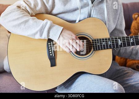Cropped shot of man practicing in playing acoustic guitar. Close-up of man hand playing guitar Stock Photo