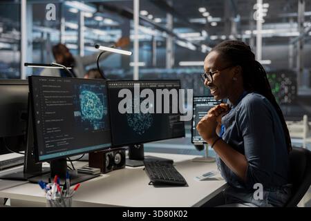 Happy engineer in data center using AI powered tech to run simulations. Cheerful employee coding cognitive computing algorithms to extract insights from data and automate rigs Stock Photo