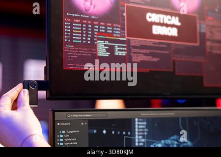 Close up of hacker using USB stick to do data breach, getting interrupted by critical error alert. Cybercriminal plugs in USB driver, trying to run AI malware, getting blocked by security systems Stock Photo