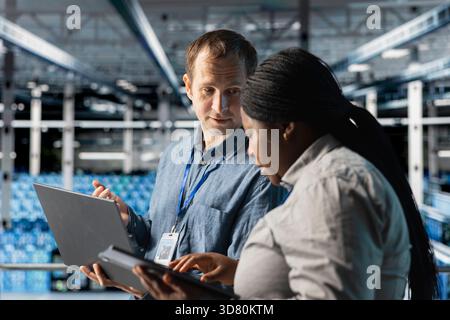 Server room coworkers auditing systems for vulnerabilities using software on laptop. Teamworking data center technicians coordinating backups and recovery protocols using notebook Stock Photo