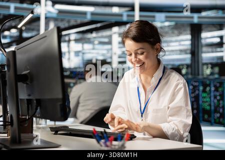 Radiant programmer in data center excited by infrastructure health report showing stable performance indicators. Overjoyed woman in server farm delighted after successfully completing operations Stock Photo