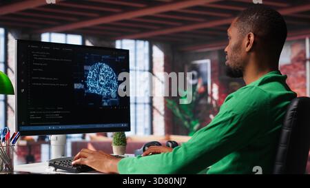 African american engineer coding a neural network AI brain model for machine learning and deep learning, solving IT support tasks on pc. Debugging software and checking for errors. Camera A. Stock Photo