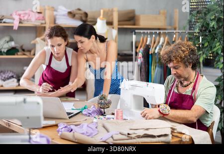 Female dressmaker and client review sketches on laptop Stock Photo