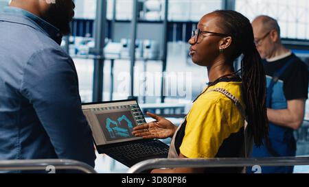 Engineers meeting with smart factory investor, showing insights based on collected data. Specialists discussing with industrial plant shareholder, presenting metrics gathered by sensors, camera A Stock Photo