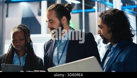 Team of photovoltaics factory engineers working together to improve solar panels efficiency. Teamworking solar panels manufacturing plant experts researching cheaper solar solutions, camera B Stock Photo