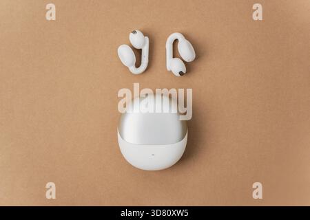 Wireless acoustic headphones with charging case on beige background. Top view. Stock Photo