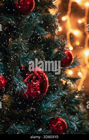 Christmas decorations on fir tree with red ornaments and Christmas lights on the background, closeup. Stock Photo