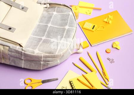 Stylish school backpack with different stationery supplies on lilac background Stock Photo