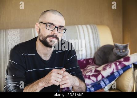 Portrait of a man sitting on a sofa with his cat Stock Photo