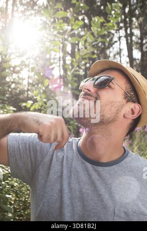 Outdoor lifestyle portrait of young hipster man wearing vintage sunglasses and plaid shirt, relaxed and enjoy nice sunny day Stock Photo