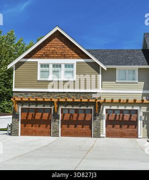 Fragment of brand new farmer's house with three garage doors and concrete driveway on blue sky background. Basketball ring in front of huge farmer's h Stock Photo