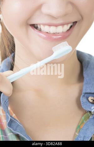 Closeup shot of asian woman brushing teeth with smiling Stock Photo