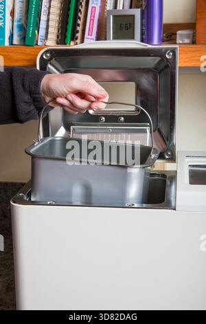 Woman placing pan of ingredients into breadmaker machine. (MR) Stock Photo