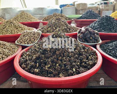 Piles of walnuts, pistachios, dates, and nuts in red bins at a bazaar Stock Photo