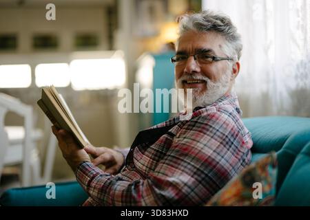 Older man enjoying a book while sitting comfortably Stock Photo