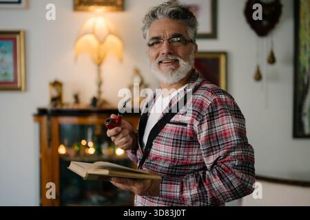 Senior man enjoying a quiet moment with a book and pipe Stock Photo