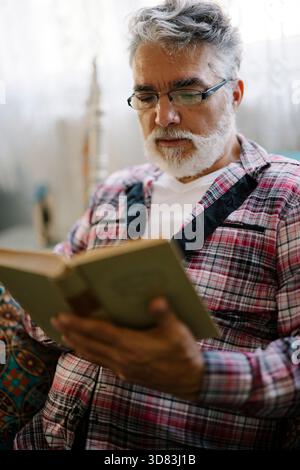 Senior man in plaid shirt reading a book Stock Photo