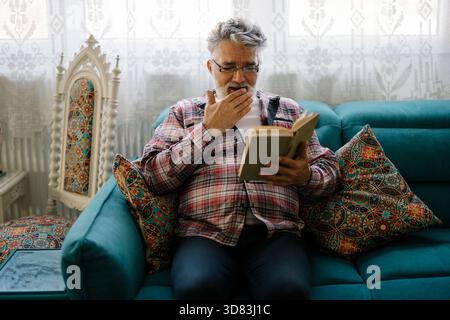 Senior man enjoys reading an interesting book while relaxing Stock Photo