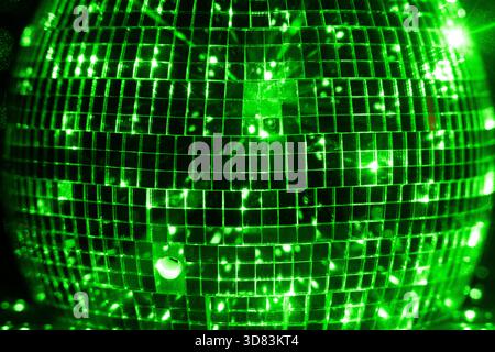 Green lights reflected in disco ball on black backdrop Stock Photo