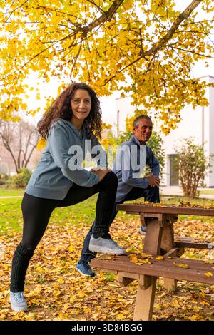 Senior couple warming up and exercising outdoors in an autumn park Stock Photo