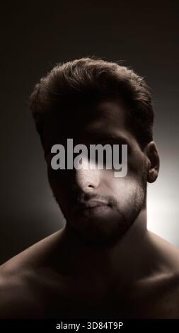 Dramatic portrait of man with post-procedure nose bandage in focused side lighting Stock Photo