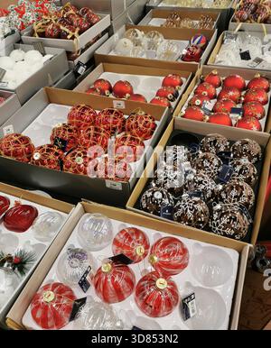 Several boxes contain Christmas ornaments in a store. The ornaments are in various styles and colors. France Stock Photo