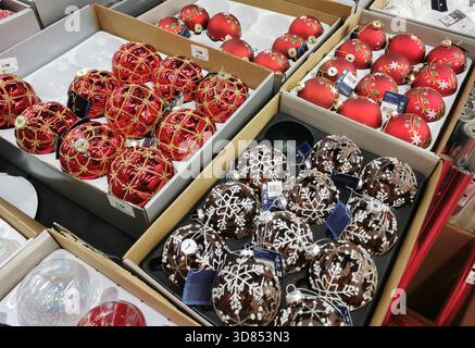 Several boxes contain Christmas ornaments in a store. The ornaments are in various styles and colors. France Stock Photo