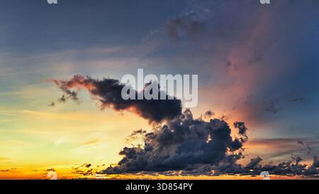 Dramatic Contrast of Dark Clouds Against a Fiery Sunset Sky Stock Photo