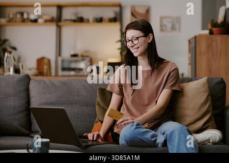 Young Adult Caucasian Woman Shopping Online Using Laptop and Credit Card Stock Photo