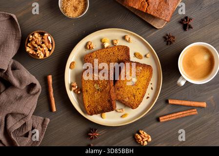 Slices of pumpkin bread with raisins and nuts on plate on brown wooden background. Top view, flat lay Stock Photo