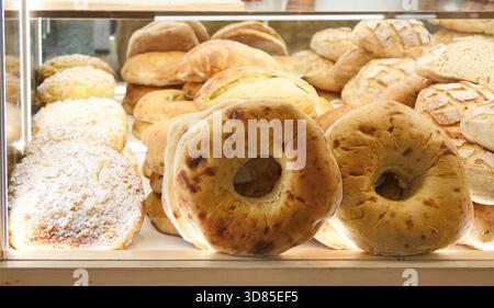 Assorted freshly baked breads are beautifully arranged in a bakery display, showcasing different textures and inviting aromas for customers to savor Stock Photo