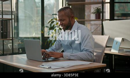 African American 40s business man typing laptop web service cyberspace adult businessman working online at office smiling mature male executive worker Stock Photo