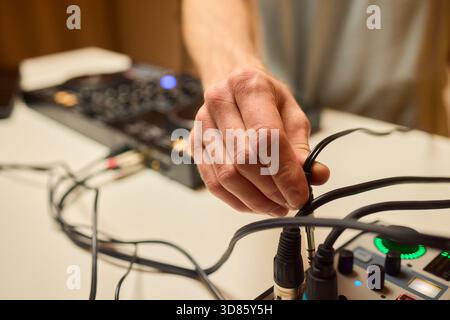 Engineer finetuning sound signals using patch cables, Focused technician adjusting levels on electronic patch cable setup with vivid colorful plugs Stock Photo