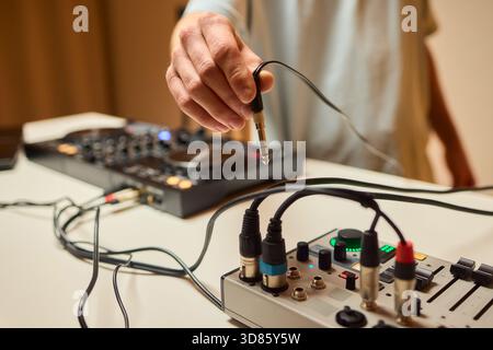 Engineer finetuning sound signals using patch cables, Focused technician adjusting levels on electronic patch cable setup with vivid colorful plugs Stock Photo